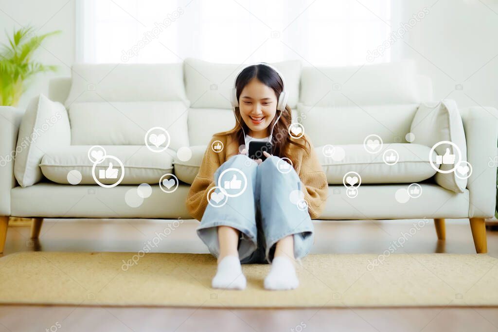 Young asian woman using mobile smartphone with icon social media and social network in living room