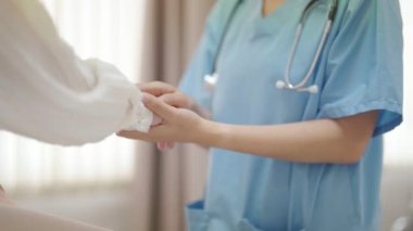 Muayene odasında hastayı rahatlatan kadın doktorun eli. Kadın doktor ve hasta hastalığın semptomları hakkında görüşmeler yapıyorlar.