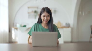 Asyalı bir kadının kazanmasını ya da bilgisayar laptopunda ecommerce alışveriş teklifi almasını kutlayan komik bir coşku. Heyecanlı mutlu kız kazanan başarıyı kutlayan deftere bakıyor.