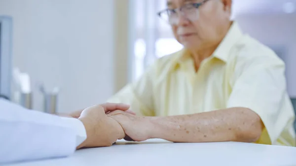 Hand of doctor comforting patient at consulting room. Doctor and patient are discussing consultation about symptom problem diagnosis of disease