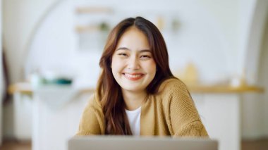 Kameraya bakan Asyalı genç bir kadının portresi. Yüz ifadesi mutlu.