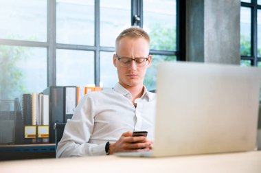 Ofiste çalışan bir iş adamı. İş yerindeki bilgisayarda çalışan yakışıklı genç adam.