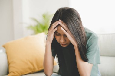 Upset asian woman frustrated by problem with work or relationships, sitting on couch, feeling despair and anxiety, loneliness, having psychological trouble