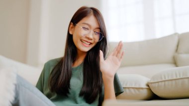 Evde dizüstü bilgisayarla çalışan gülümseyen Asyalı kadın. Çekici Asyalı kadın bilgisayar eğitimi kullanıyor, çevrimiçi eğitim ve video çağrısı izliyor.