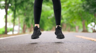 Asyalı kadın, halka açık parkta spor yaparken bacağını ve bileğini ısıtıyor. Zıpladı ve bileğini burktu. Sağlıklı yaşam tarzı konsepti, parkta spor faaliyetleri