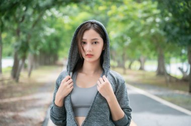 Ceket giyen Asyalı kadın halk parkında spor yapıyor. Sağlıklı yaşam tarzı konsepti, parkta spor faaliyetleri