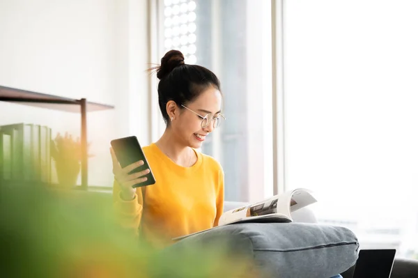 Happy Young Asian Woman Reading Sofa Holding Mobile Smartphone Living — Foto Stock