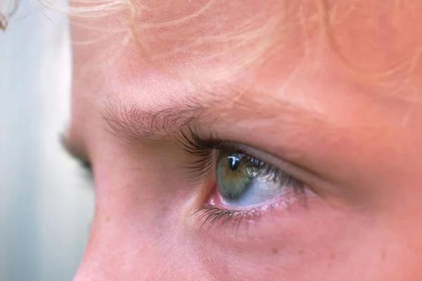 A close-up of the child\'s eye. A man looks into the distance. Reflection of the lens in the eye.