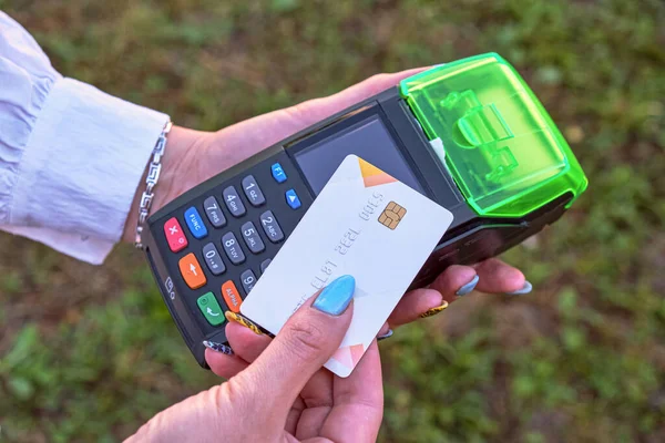 Close-up of a credit card and a payment terminal. Contactless bank card with NFC technology. A woman makes a payment