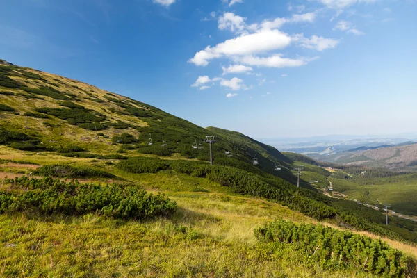 查看山在夏天与蓝蓝的天空背景上的滑雪缆车 — 图库照片