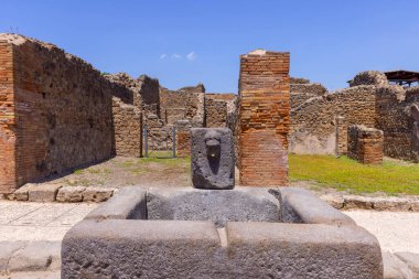 Ruins of an ancient city destroyed by the eruption of the volcano Vesuvius in 79 AD near Naples, Pompeii, Italy. A fountain for public use on one of the streets clipart