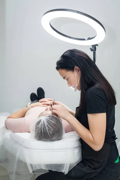 Ustabaşı müşterinin kaşlarını koparır. Kanepenin üstündeki selfie aynası..