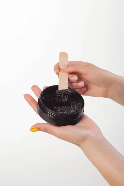 Beyaz arka planda siyah bir kavanozu fırçalayarak. Eller değneği tutsun.