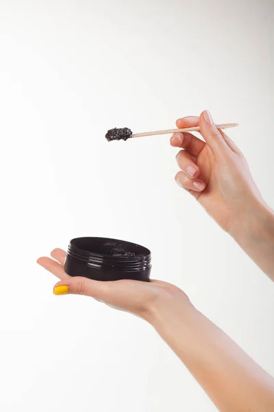 Beyaz arka planda siyah bir kavanozu fırçalayarak. Eller değneği tutsun.