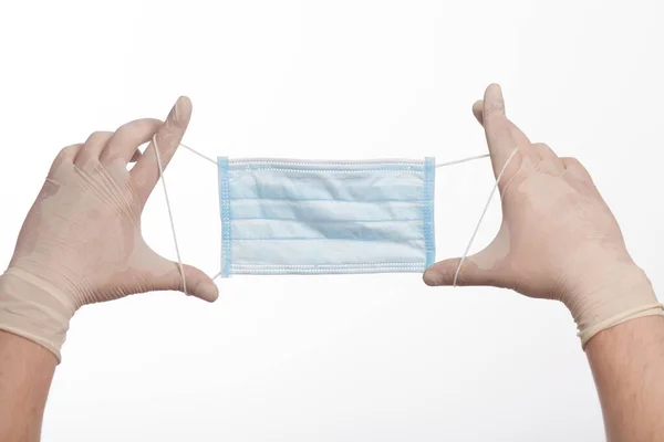 Tıbbi maske, beyaz bir arka planda eldivenle erkek elinde.