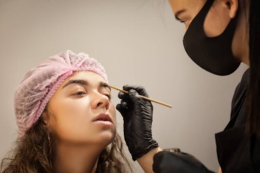 Güzel genç bir kadın kaş düzeltme prosedürünü uyguluyor. Güzellik salonunda kaşlarını boyayan genç bir kadın..