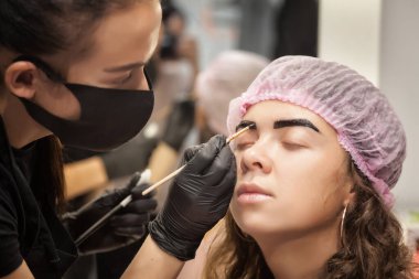 Güzel genç bir kadın kaş düzeltme prosedürünü uyguluyor. Güzellik salonunda kaşlarını boyayan genç bir kadın..