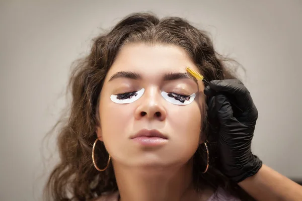 Güzel genç bir kadın kaş düzeltme prosedürünü uyguluyor. Güzellik salonunda kaşlarını boyayan genç bir kadın..