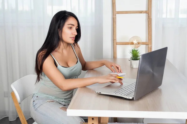 Masadaki esmer kız koltukları ve defterle çalışmak. 