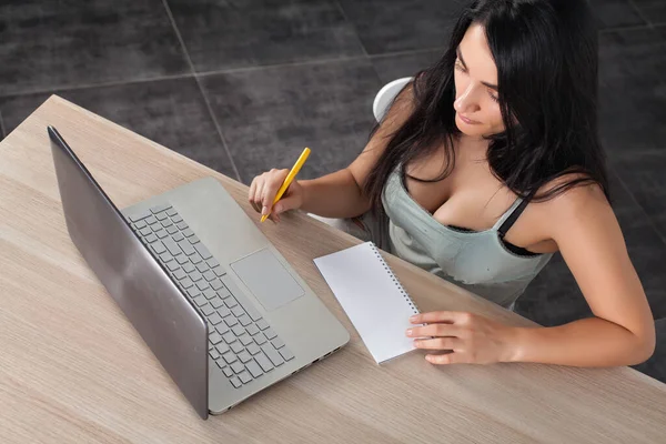 Masadaki esmer kız koltukları ve defterle çalışmak. 