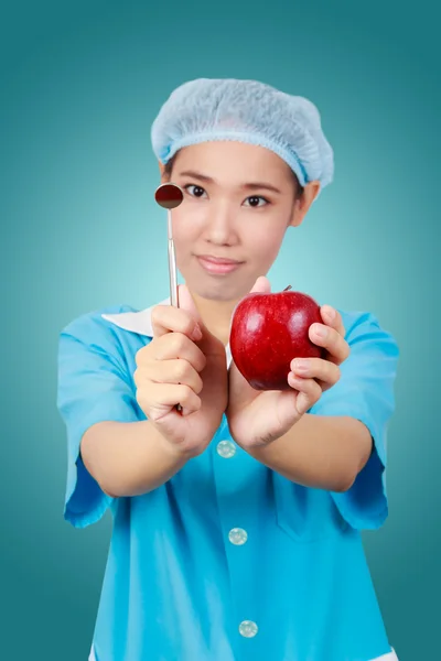 Female dentist holding an apple and metal medical equipment too — Stock Photo, Image
