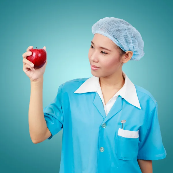 Female dentist holding an apple and metal medical equipment too — Stock Photo, Image