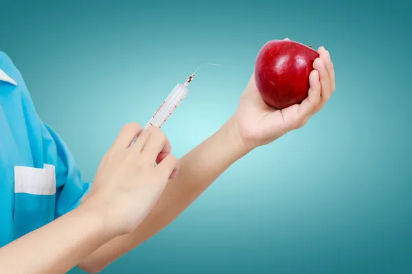 Female dentist holding an apple and syringes for teeth dental ca — Stock Photo, Image