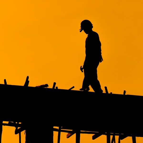 Silueta de los trabajadores de la construcción en andamio trabajando bajo una h — Foto de Stock