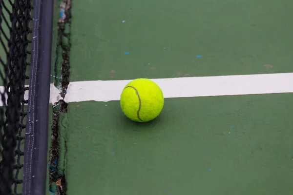 Tennisboll på domstolen på nära håll med netto i bakgrunden — Stockfoto