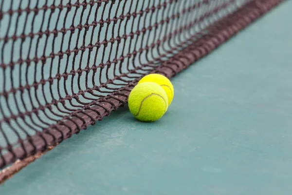 Tennisboll på domstolen på nära håll med netto i bakgrunden — Stockfoto