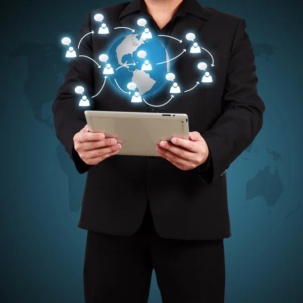 Businessman holding a tablet with globe and community icons. Con — Stock Photo, Image