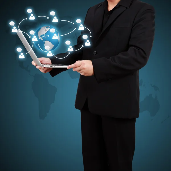 Businessman holding a laptop with social network icons coming ou — Stock Photo, Image