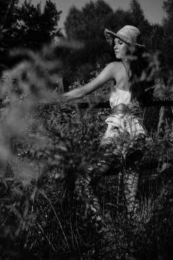 Yazlık giysiler içinde, çayırda hasır şapkalı güzel bir genç kadının klasik fotoğrafı, mutluluk yazı. 