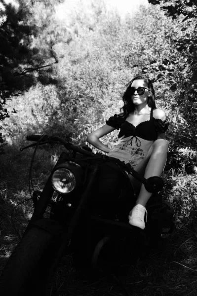 年轻性感的女人 留着长长的波浪般的头发 穿着夏天的衣服 摆出摩托车的姿势 黑白照片 — 图库照片