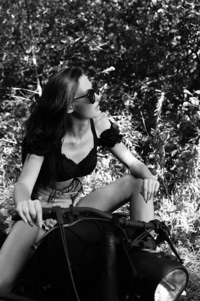 年轻性感的女人 留着长长的波浪般的头发 穿着夏天的衣服 摆出摩托车的姿势 黑白照片 — 图库照片