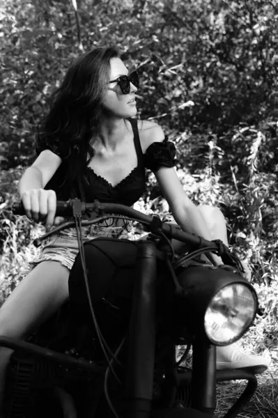 長い波状の髪をした若いセクシーな女性がバイクでポーズをとっています 白黒写真 — ストック写真