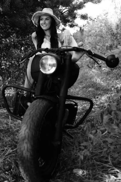 夏服の長い波状の髪をした若いセクシーな女性とバイクの近くにポーズを藁帽子 白黒写真 — ストック写真