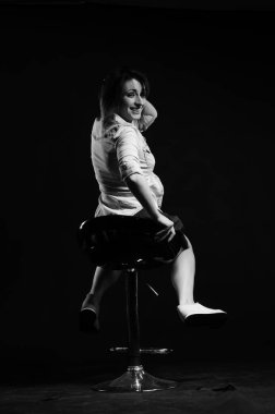 Stüdyoda siyah arka planda poz veren güzel genç bir kadın, moda tarzı, siyah beyaz fotoğraf.