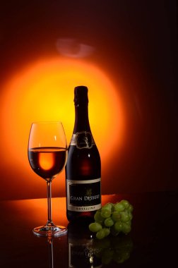 Stüdyoda bir şişe şarap ve arka planda bir demet üzüm..