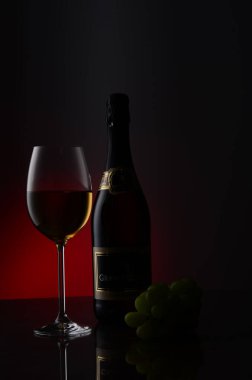 Stüdyoda bir şişe şarap ve arka planda bir demet üzüm..