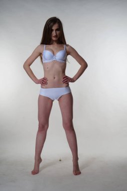 Seksi esmer kadın iç çamaşırlarıyla poz veriyor.