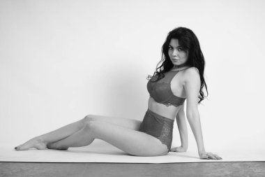 Stüdyoda iç çamaşırlı güzel bir kadın poz veriyor.