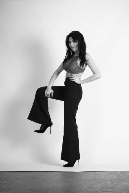 Siyah elbiseli güzel bir kadının siyah beyaz portresi stüdyoda poz veriyor.