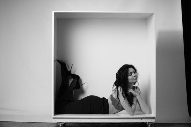 Siyah elbiseli güzel bir kadının siyah beyaz portresi stüdyoda poz veriyor.