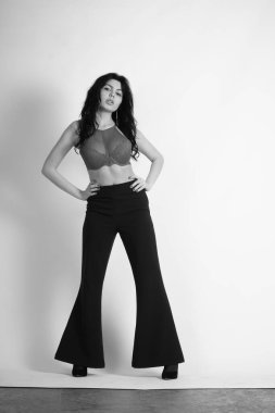 Siyah elbiseli güzel bir kadının siyah beyaz portresi stüdyoda poz veriyor.