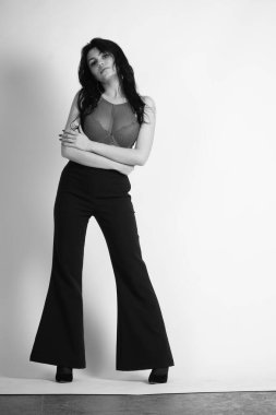 Siyah elbiseli güzel bir kadının siyah beyaz portresi stüdyoda poz veriyor.