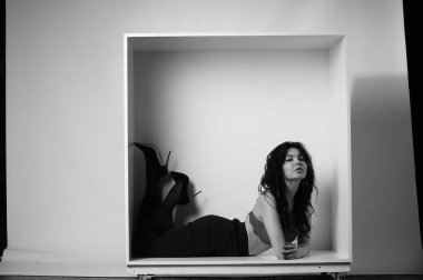 Siyah elbiseli güzel bir kadının siyah beyaz portresi stüdyoda poz veriyor.