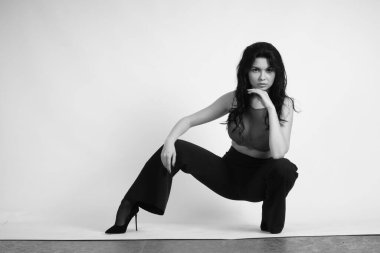 Siyah elbiseli güzel bir kadının siyah beyaz portresi stüdyoda poz veriyor.