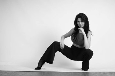 Siyah elbiseli güzel bir kadının siyah beyaz portresi stüdyoda poz veriyor.