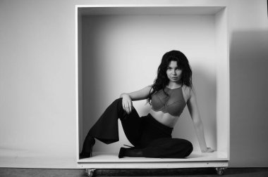 Siyah elbiseli güzel bir kadının siyah beyaz portresi stüdyoda poz veriyor.